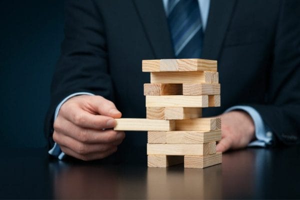 A man playing Jenga representing managing risk and uncertainty in higher interest rate environment