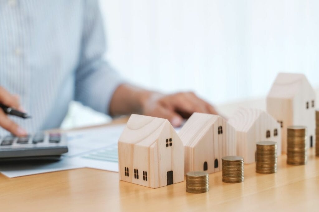 Four wooden commercial property with money next to them and a man calculating how much each property taxes is