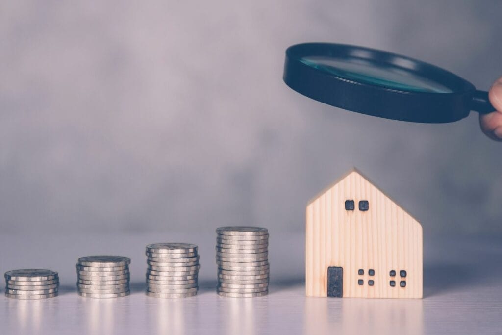 Hand of a businessman holding magnifying glass on a commercial property with money next to it in seeing the tax benefits of commercial stay investments