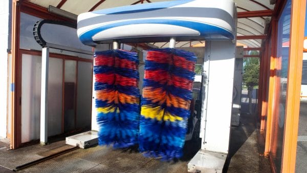 
A colorful automatic car wash bay with vibrant red, blue, and yellow brushes, indicative of the type of business being discussed in content about how to effectively market and sell a car wash.