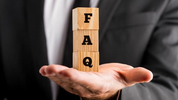 A person in a suit holds three wooden blocks stacked vertically with the letters "F," "A," and "Q," symbolizing a frequently asked questions section that might address queries about selling a 1031 exchange property. The image suggests professional guidance on the complexities involved in such real estate transactions.